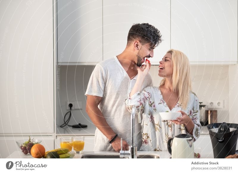 Loving couple having breakfast in modern kitchen together strawberry eat enjoy morning hug love early fresh orange juice food fruit home relationship drink