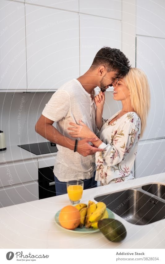 Cheerful couple hugging tenderly in kitchen embrace touch nose love together morning home domestic girlfriend boyfriend modern relationship fondness close