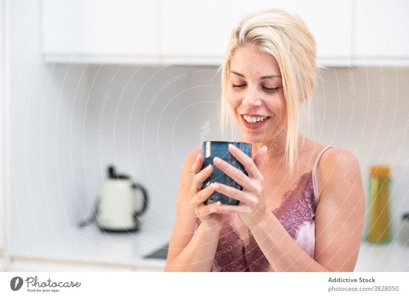 Woman drinking coffee after awakening at home morning woman breakfast energy caffeine kitchen enjoy female fresh modern table pajama silk calm apartment cup