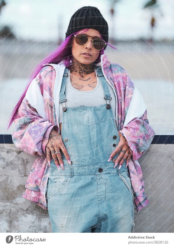 Woman in hip hop outfit in city millennial trendy fancy woman style sunglasses tattoo street style pink hair female cool young urban contemporary slim cloth