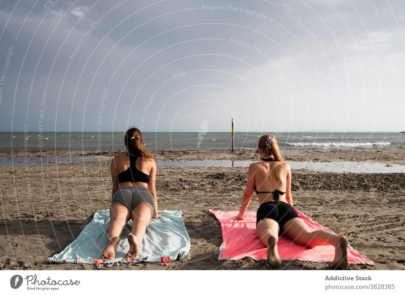 Young women lying on beach and doing Cobra pose yoga slim cobra pose perform observe ocean wavy foamy bhujangasana freedom recreation summer holiday relax zen