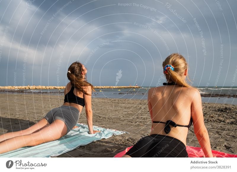 Young women lying on beach and doing Cobra pose yoga slim cobra pose perform observe ocean wavy foamy bhujangasana freedom recreation summer holiday relax zen