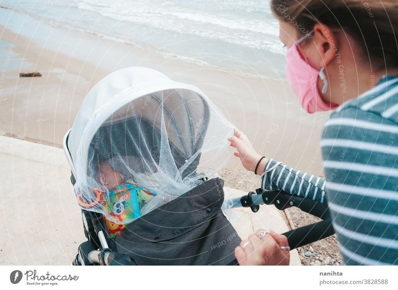 Young mom walking with her baby during covid pandemic covid-19 coronavirus motherhood family holidays mask face mask daughter beach outdoors sea shore autumn