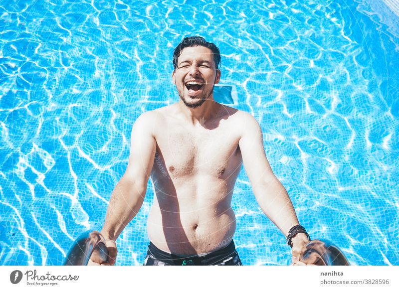 Young handsome man posing near a pool attractive sexy male swimming pool summer skin beard guy smile tan blue water party portrait portraiture real people cool