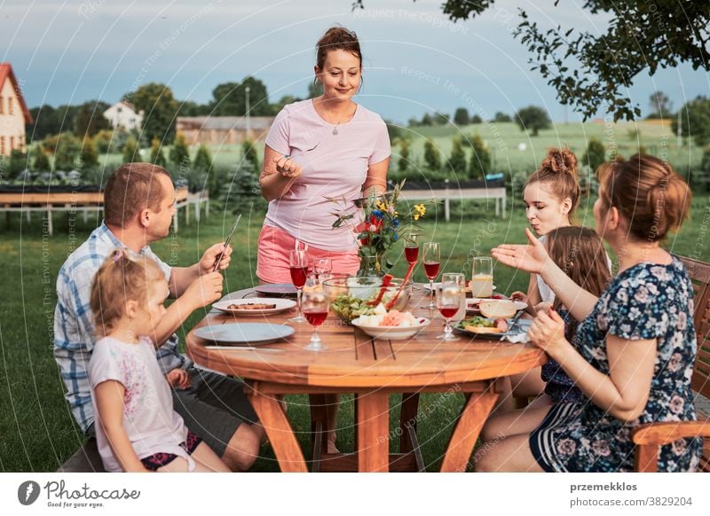 Family having a meal during summer picnic outdoor dinner in a home garden feast food man together woman child barbecue table eating gathering people lifestyle