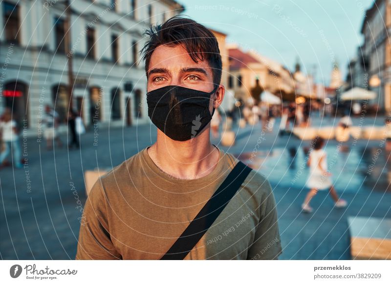 Young man standing in the city center wearing the face mask to avoid virus infection caucasian conversation covid-19 lifestyle outbreak outdoors pandemic