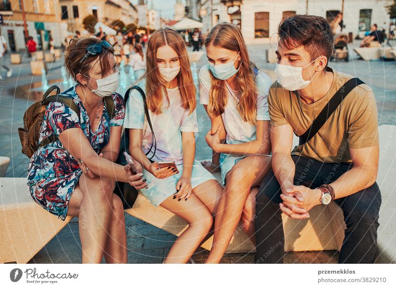 Young women spending time together sitting in the city center wearing the face masks to avoid virus infection caucasian conversation covid-19 female lifestyle