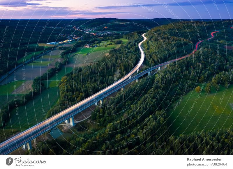 Aerial view of highway splitting aound forest hill on autumn evening, long exposure above aerial agriculture architecture blue bridge clouds countryside europe