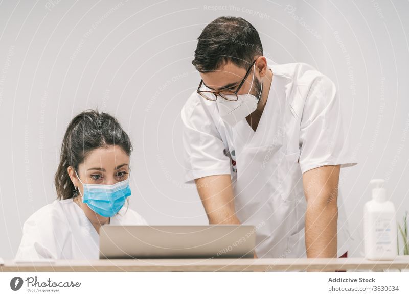 Busy doctors working on laptop in hospital clinic together colleague mask professional job occupation netbook device health care computer concentrate staff