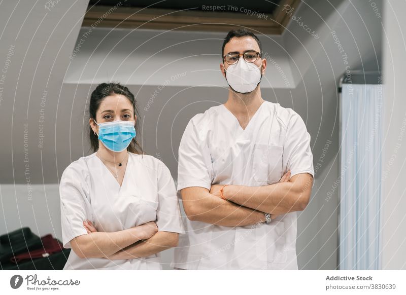 Smiling doctors in uniform and mask looking at camera medic hospital staff cheerful smile occupation specialist professional medical stand service medicine