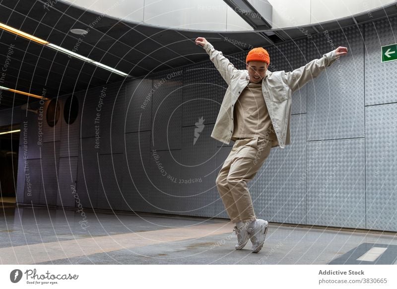 Cheerful Asian man standing on tiptoes in building hallway posture happy dance cheerful outstretch motion dynamic cool style excited carefree joy positive