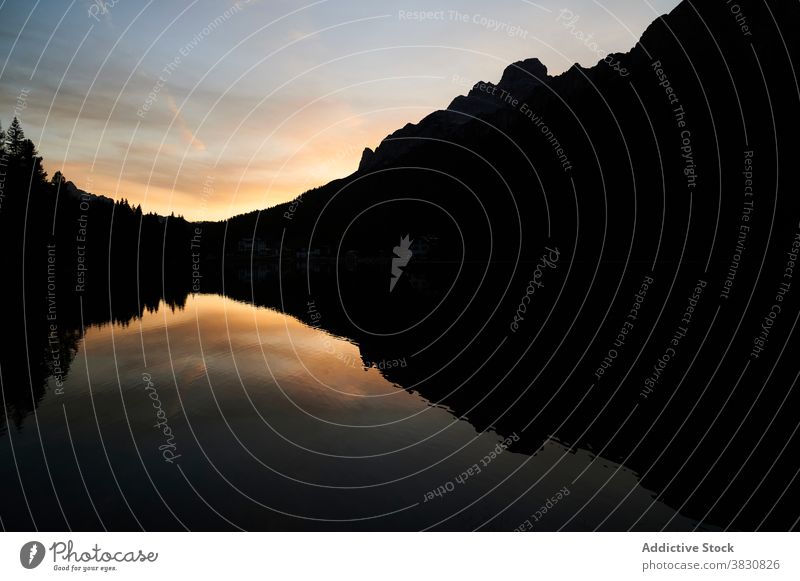 Calm lake and mountains at sunset evening dusk twilight pond highland range ridge the dolomites italy sundown sky calm picturesque breathtaking nature