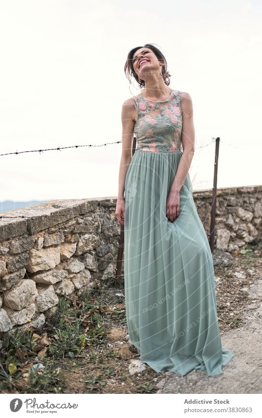 Happy slender woman next to stone fence in daytime skinny cheerful toothy smile fashion style gorgeous happy outfit female content glad glamour dress allure