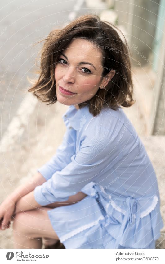 Happy woman resting on curb and looking at camera cat thoughtful watch cheerful street skinny relax facade female happy lean on hand animal pet feline comfort