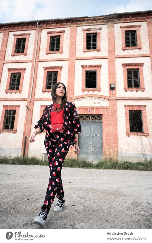 Thoughtful woman walking on ground by deserted construction stroll exterior street architecture building thoughtful outfit style female serious trendy shabby