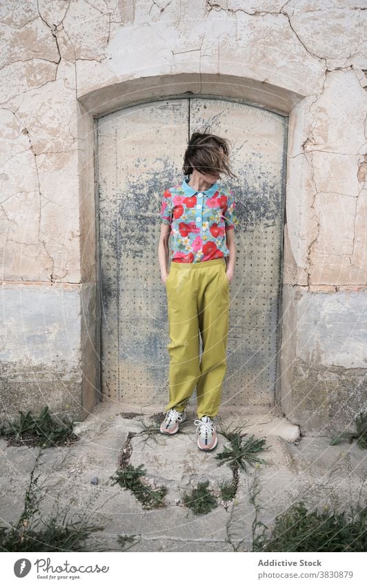 Slender woman next to shabby door of old building architecture outfit messy hair fashion slender slim style construction female stand calm trendy daytime think