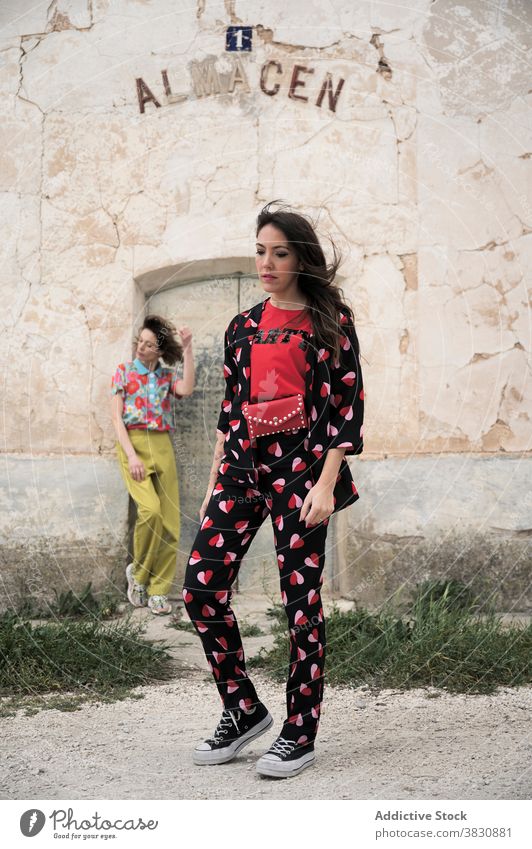 Dreamy women with flying hair on street fashion outfit slender architecture exterior weathered charming brunette beautiful allure touch hair crack grass house