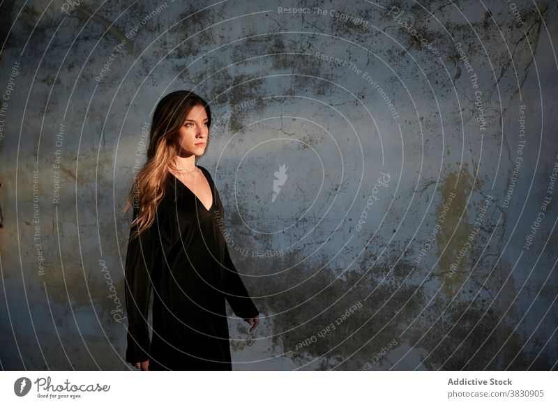 Woman in black dress standing near weathered building woman shabby wall aged grunge alone gloomy depression young female exterior ancient house calm tranquil