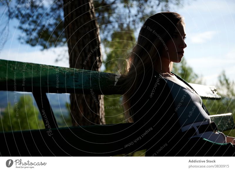 Relaxed woman resting on bench in forest contemplate relax sunlight nature woods calm peaceful pensive dream thoughtful young female tranquil lifestyle enjoy