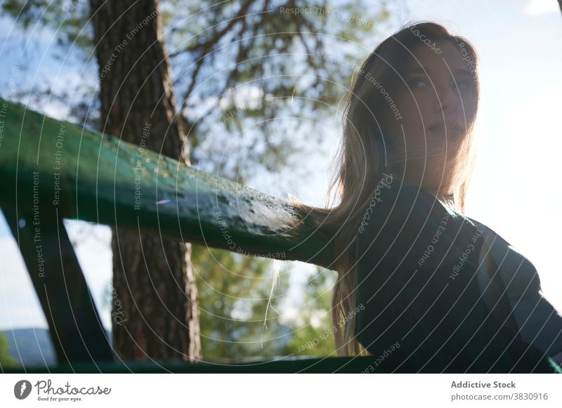 Relaxed woman resting on bench in forest contemplate relax sunlight nature woods calm peaceful pensive dream thoughtful young female tranquil lifestyle enjoy