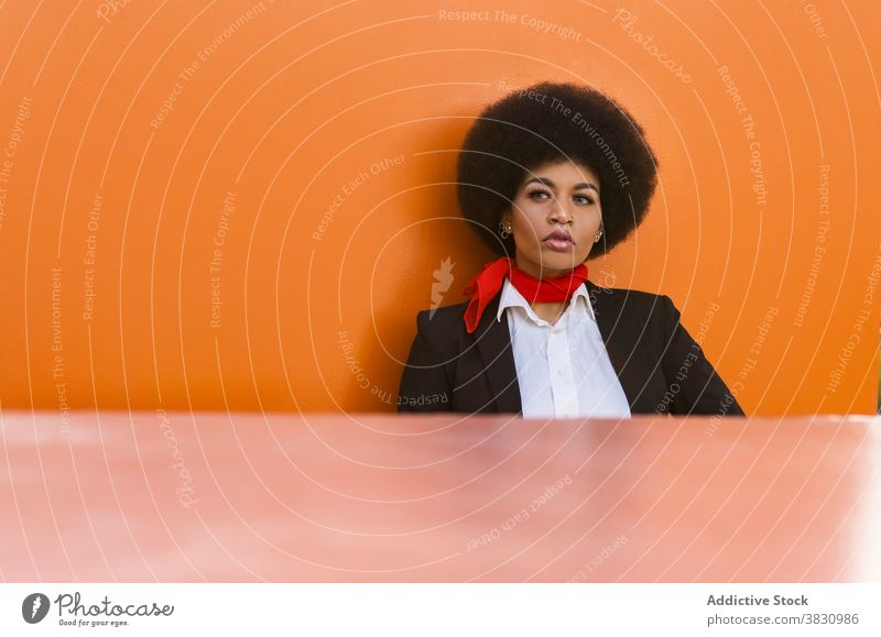 Confident black woman in formal outfit standing near colorful wall concentrate employee elegant occupation worker respectable style confident female serious