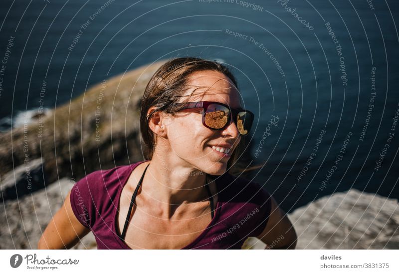 Happy natural woman portrait, with sunglasses, enjoying outdoors in the coast. exercise cheerful carefree happy relax standing waves sunny seashore coastline