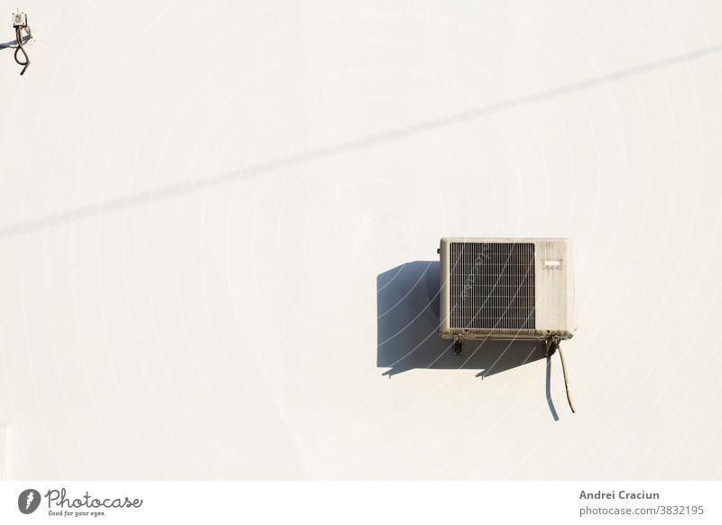 Old air conditioning machine installed on a white wall, with harsh mid day sunlight air conditioner appliance background change climate comfort cool cooling