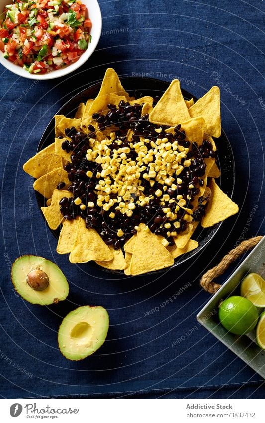 Chilaquiles dish with avocado food chilaquiles mexican tortilla top view breakfast overhead black beans nachos cilantro sauce fried meal chips fresh salsa