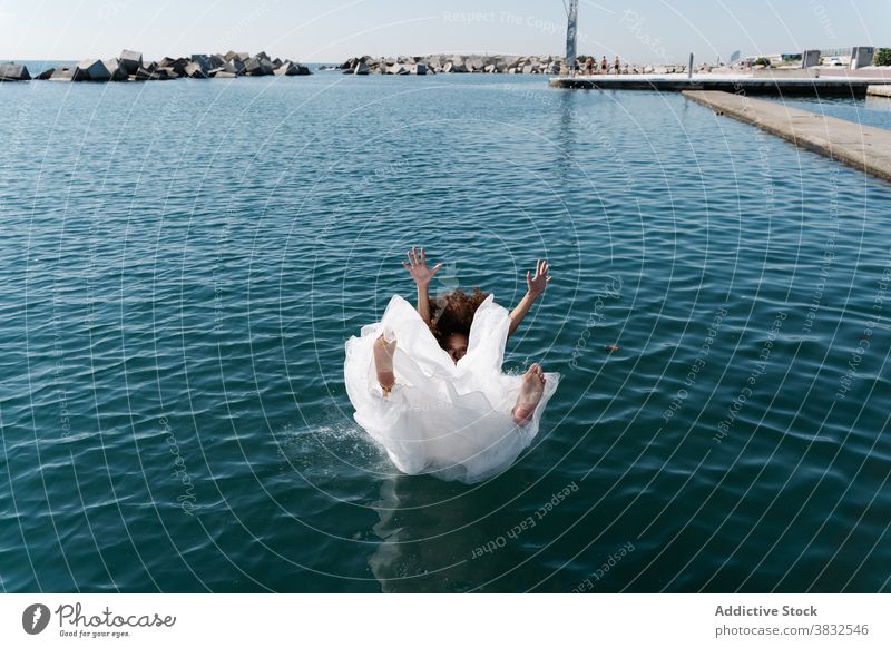 Anonymous woman in bridal dress falling in water white dress barefoot seafront lake pier young excited drown fun funky embankment afraid bodacious confused