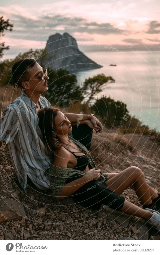 Carefree couple resting on hill near sea style sunset relax enjoy carefree love cuddle shore relationship tranquil stone rough summer romantic coast nature