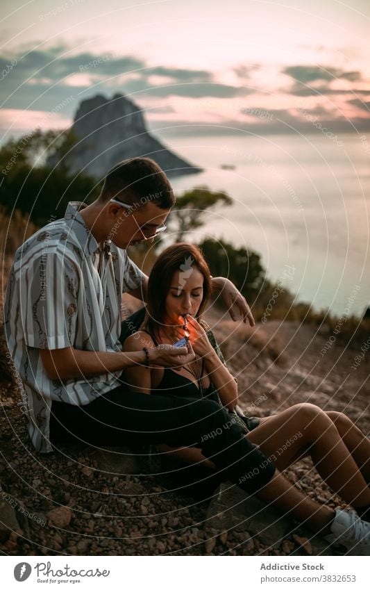 Couple smoking cigarettes at seaside smoke couple relax lighter together girlfriend boyfriend sunset seashore love vacation romantic calm evening nicotine habit