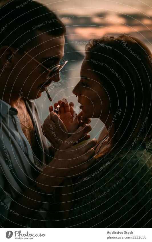 Couple smoking cigarettes at seaside smoke couple relax lighter together girlfriend boyfriend sunset seashore love vacation romantic calm evening nicotine habit