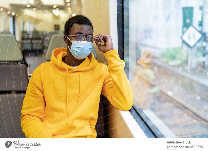 Ethnic man in medical mask sitting in modern train passenger traveler window tourist new normal coronavirus male ethnic black african american seat trip