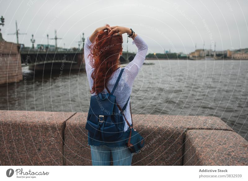 Woman enjoying fresh wind near river in city woman urban freedom traveler bridge sightseeing red hair female redhead tourist saint petersburg russia relax rest