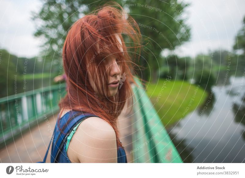 Hipster woman with backpack standing on footbridge over river traveler island hipster pathway alone explore pedestrian saint petersburg russia