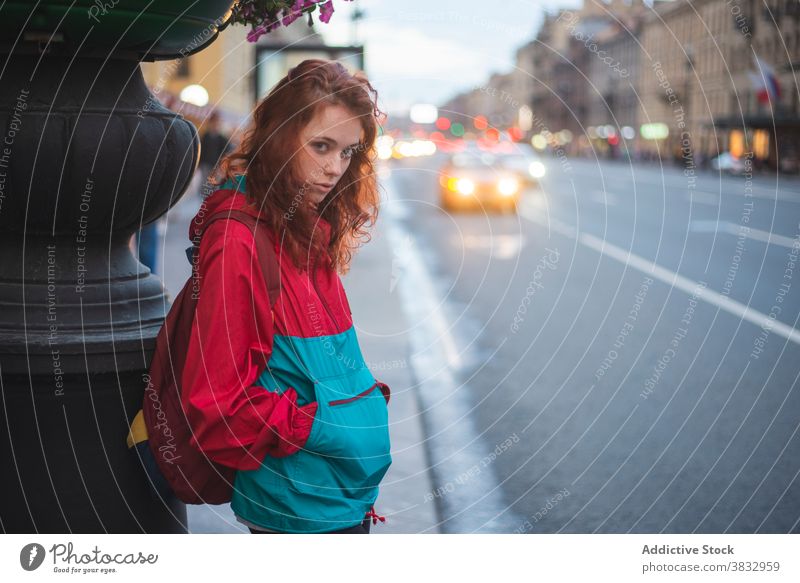 Young red haired woman standing near road in city redhead urban young wind serious millennial street curly hair long hair female saint petersburg russia travel