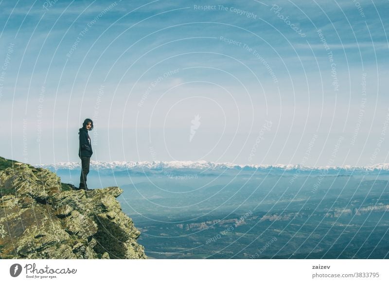 A girl on the top of a rock looking at the camera landscape hills mounts mountains extension slope background views nature day daylight hiking trekking