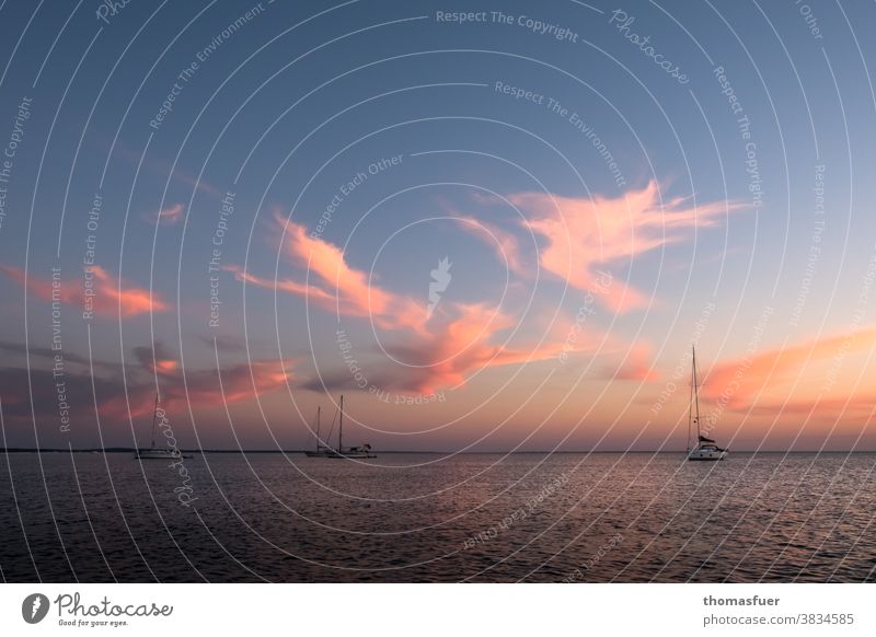 Sunset at the sea with sailboats at anchor, gently calm atmosphere, interesting clouds Ocean Water Sky Clouds Horizon Twilight Evening tranquillity coast