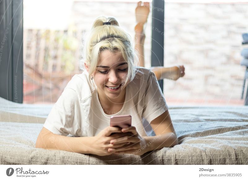 Close-up portrait of sweet attractive charming cute lovely adorable stunning cheerful blond lady lying on bed chatting boyfriend or husband in light white interior room indoors