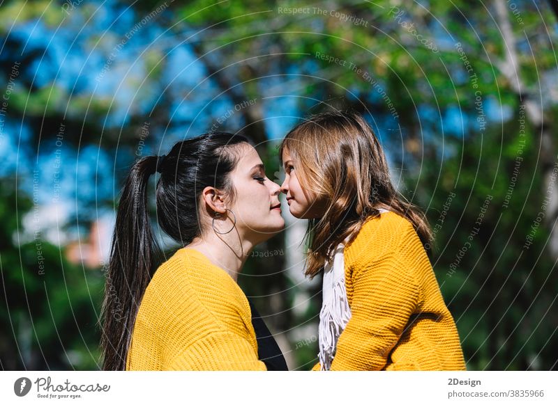 Little cute child baby girl kiss on cheek and hug, embrace with happy pretty woman in green park. Mother, little kid daughter. Mother's Day, love family, parenthood, childhood