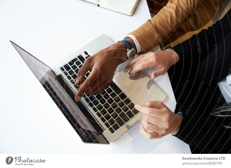 Close Up Of Businessman And Businesswoman At Hot Desk Meeting And Working On Laptop In Modern Office business businessman businesswoman meeting office hot desk