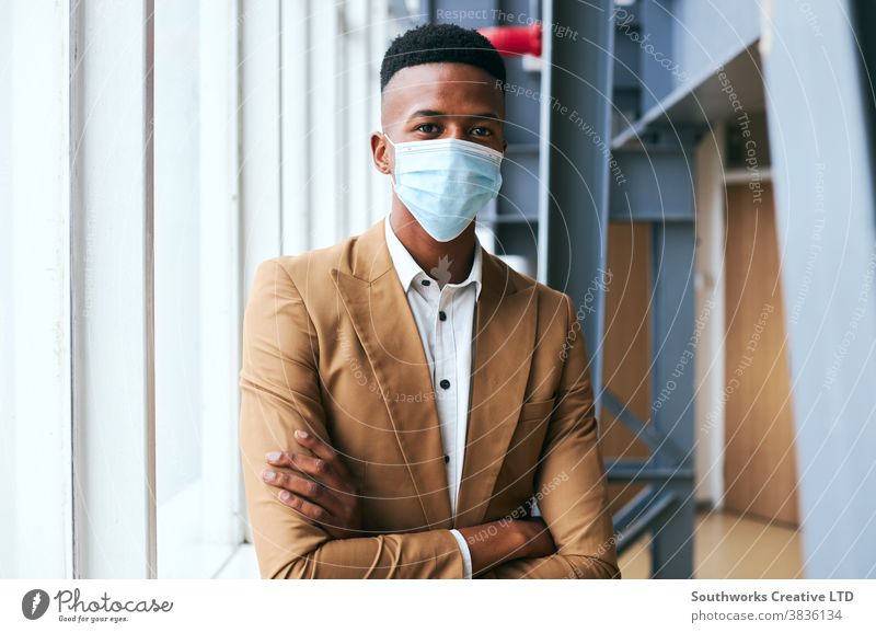 Portrait Of Young Businessman Wearing Mask Standing In Modern Office During Health Pandemic business businessman face mask face covering wearing ppe working