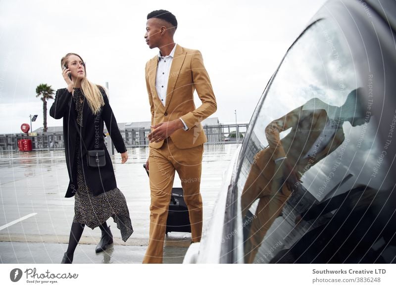 Business Couple With Luggage Arriving Outside Airport For Business Trip As Woman Uses Mobile Phone business businessman businesswoman airport luggage suitcase