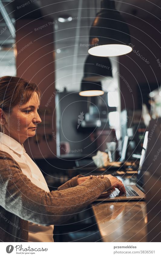 Businesswoman working remotely on her laptop managing her work sitting in a cafe business caucasian computer connection desk entrepreneur female indoors