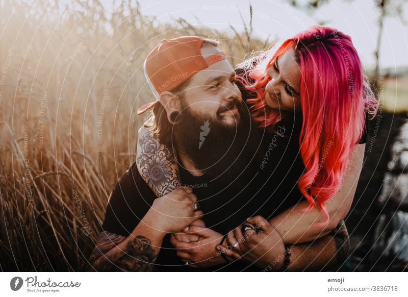 Couple with tattoos and pink hair hug and look at each other Woman Man Hipster Hip & trendy Cuddling heartfelt Tattoo Cornfield Field out Love In love Sunset