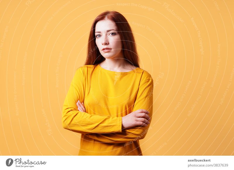 colorful studio portrait of confident young woman with her arms folded adult person people yellow orange background female beautiful attractive girl pretty