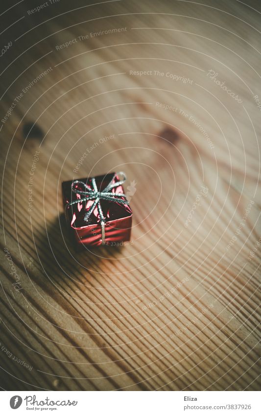 Small red gift on a wooden table Wood Gift Christmas gift Giving of gifts Packaging Surprise Anticipation Birthday Bow Red