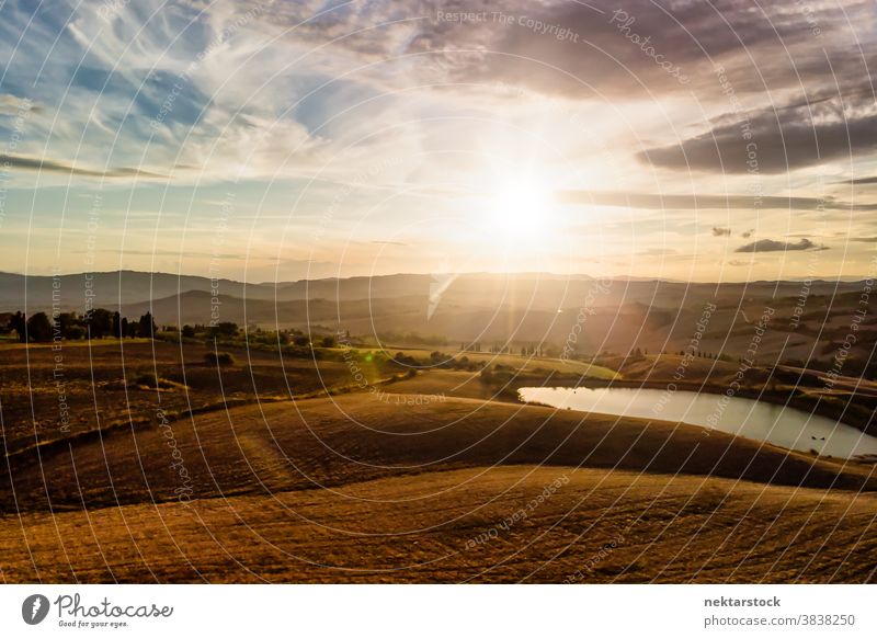 Italian Landscape Panorama with Silhouetted Mountains and Cloudscape Tuscany Italy landscape cloudscape panorama agriculture field lake sun sunrise rural