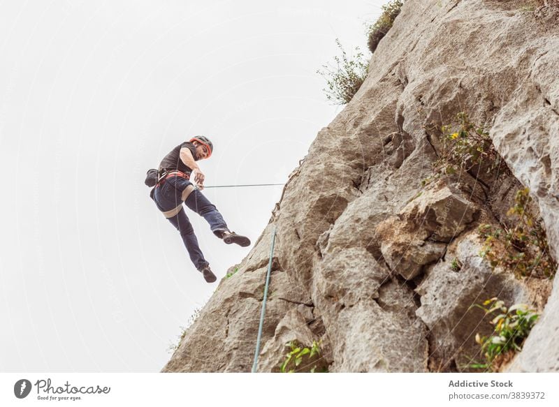 Male climber ascending on sheer cliff in summer man alpinist mountain practice climbing active mountaineering male risk travel extreme freedom adrenalin