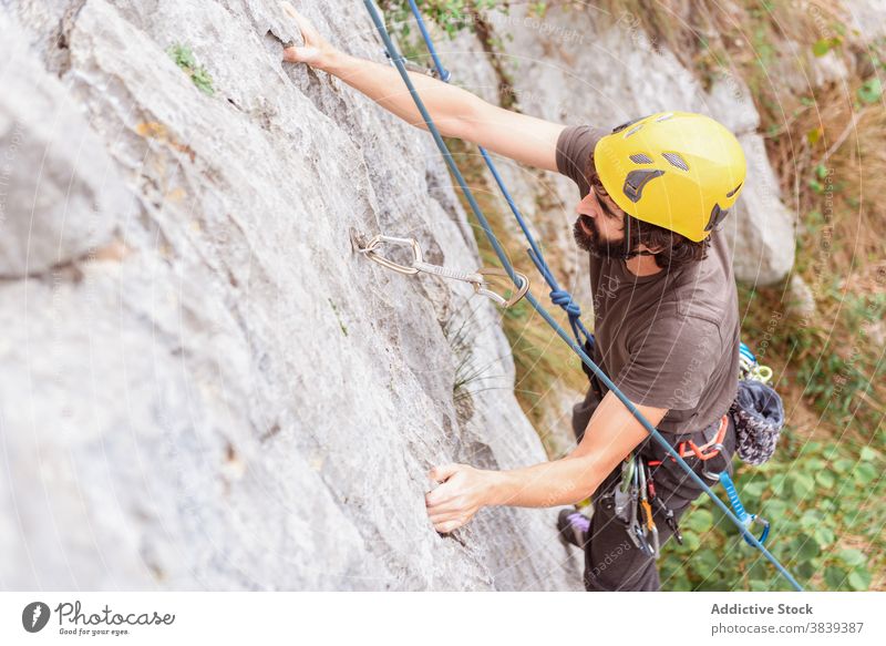 Male climber ascending on sheer cliff in summer man alpinist mountain practice climbing active mountaineering male risk travel extreme freedom adrenalin